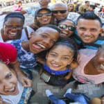 Un grupo de inmigrantes cubanos contentos, se toman una selfie, en medio de una cola para inscribirse en clases de inglés.