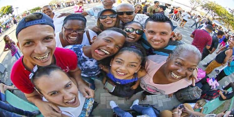 Un grupo de inmigrantes cubanos contentos, se toman una selfie, en medio de una cola para inscribirse en clases de inglés.